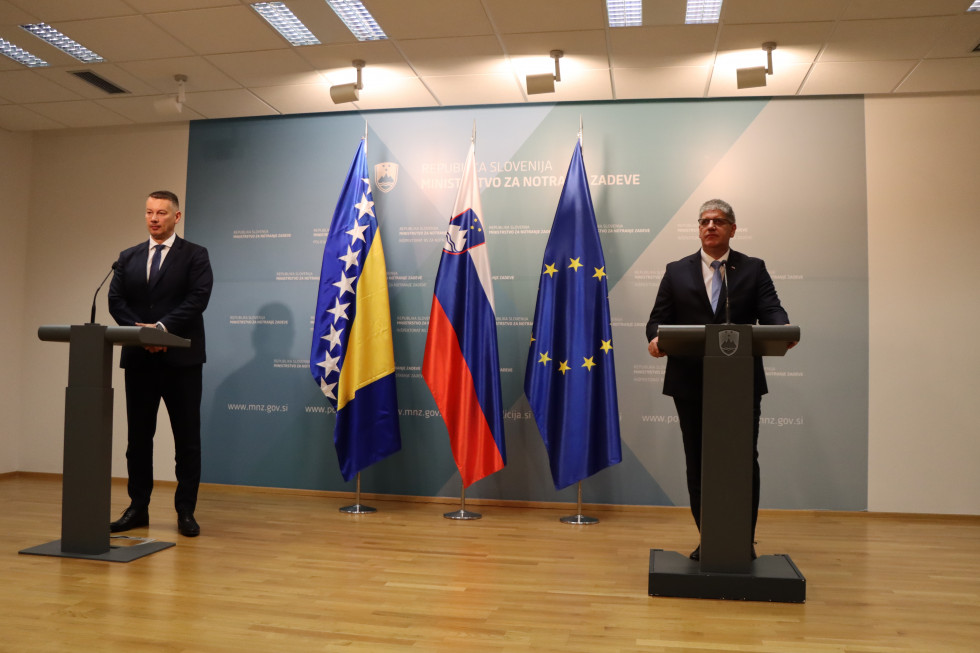 Public statement after the bilateral meeting of Ministers Poklukar and Nešić. They stand in the hall, each behind their lectern. Behind them is a blue banner and flags.