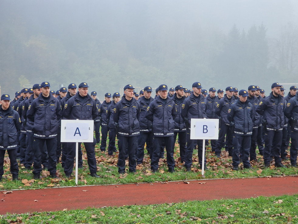 7. generacije diplomantov Višje policijske šole stoji na travniku v kolonah, pred njimi so table, ki označujejo vrste.