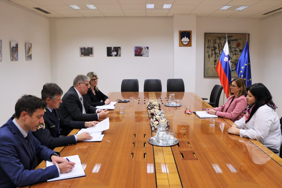Za veliko rjavo mizo sedijo predstavniki ministrstva za notranje zadeve, nasproti njih pa predstavnici Javne agencije Republike Slovenije za varnost prometa, v ozadju so manjše slike in slovenska zastava.