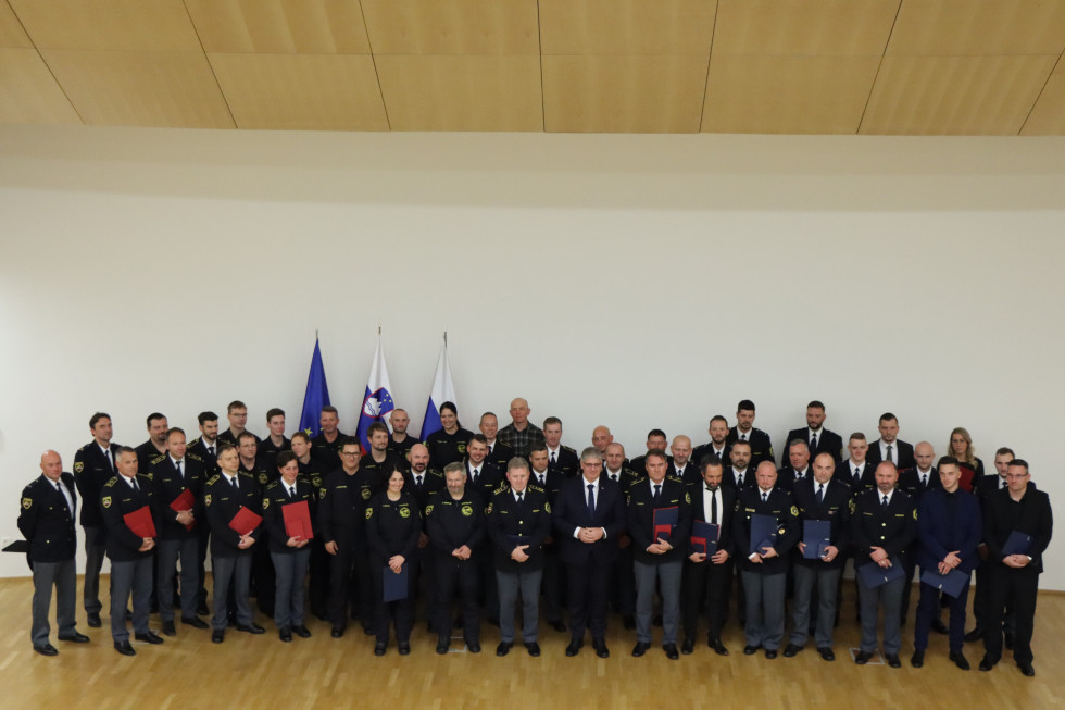 Pred belo steno so se fotografirali vsi dobitniki priznanj, skupaj z ministrom Boštjanom Poklukarjem in namestnikom generalnega direktorja policije Igorjem Ciperletom.