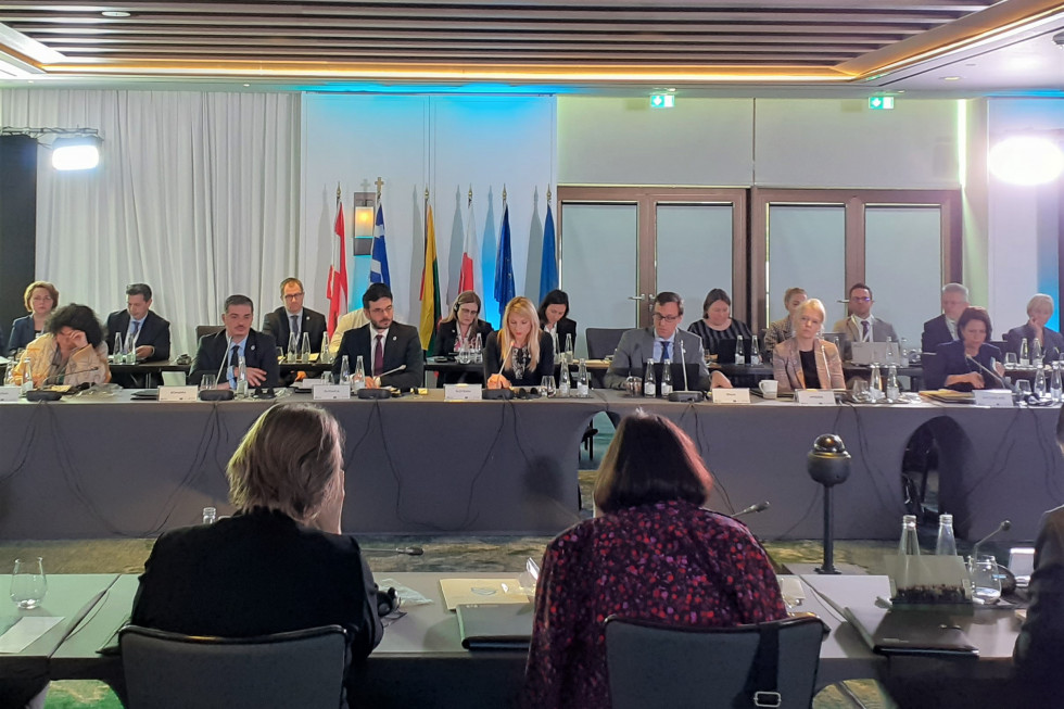 State Secretary Tina Heferle attended the 2nd European Conference on Border Management in Athens. In the conference room sitting and speaking, flags in the background
