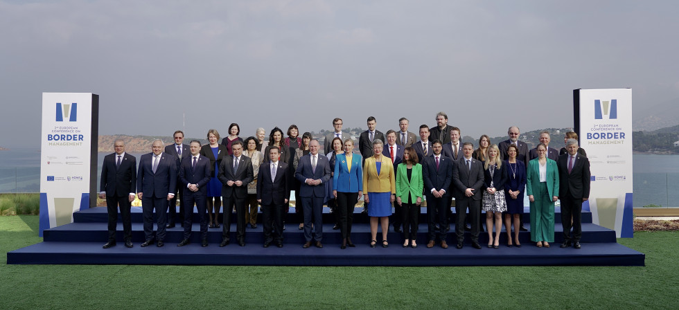Group photo of the participants. Standing on the blue podium, sky above, see in the back.