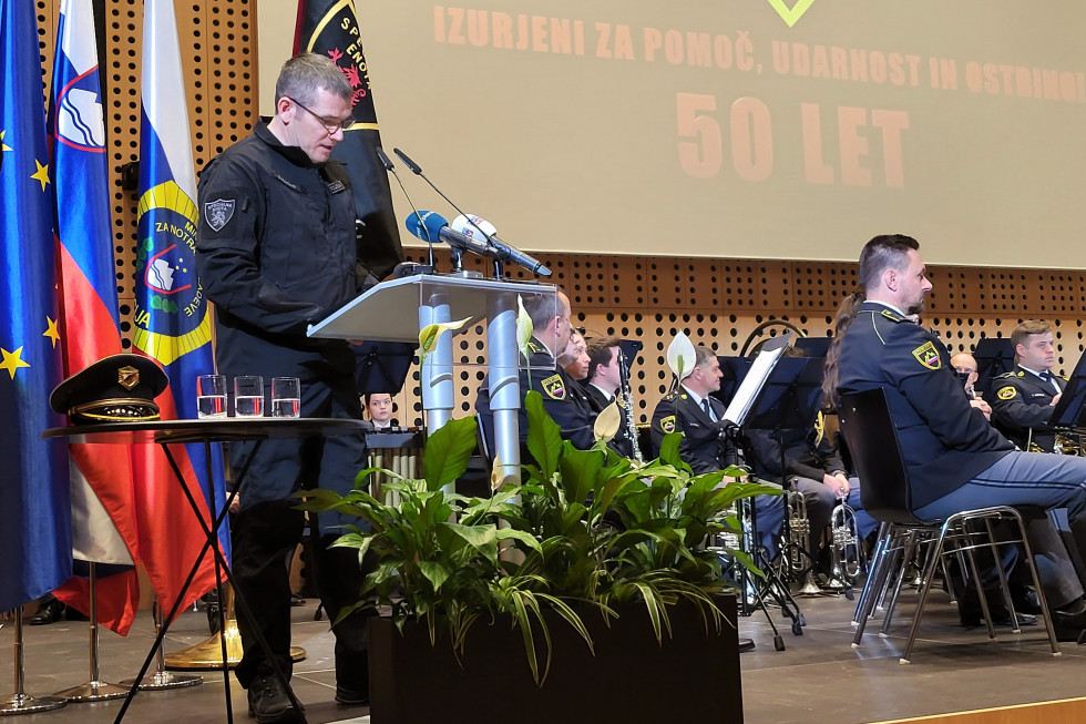 Nagovor poveljnika Specialne enote Damjana Žagarja. Stoji na odru za govornico, desno policijski orkester.