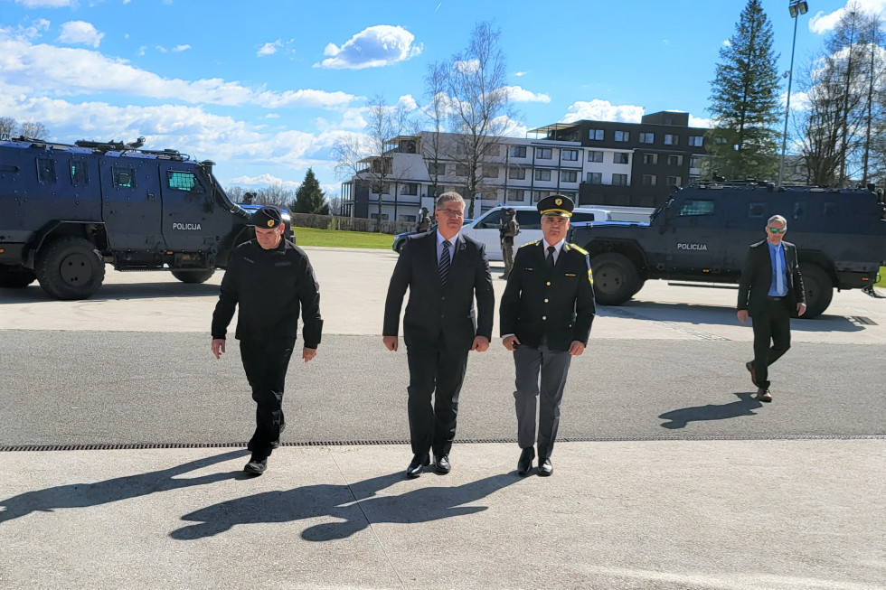 Poveljnik Specialne enote Damjan Žagar, minister za notranje zadeve Boštjan Poklukar in vršilec dolžnosti generalnega direktorja policije mag. Senad Jušić hodijo po ploščadi. Zadaj dve specialni policijski vozili. Lep sončen dan.