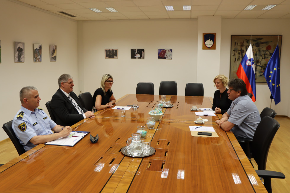 Minister Boštjan Poklukar s sodelavci in župan Ivan Molan s sodelavko sedijo za rjavo pravokotno mizo, za njimi bela stena.