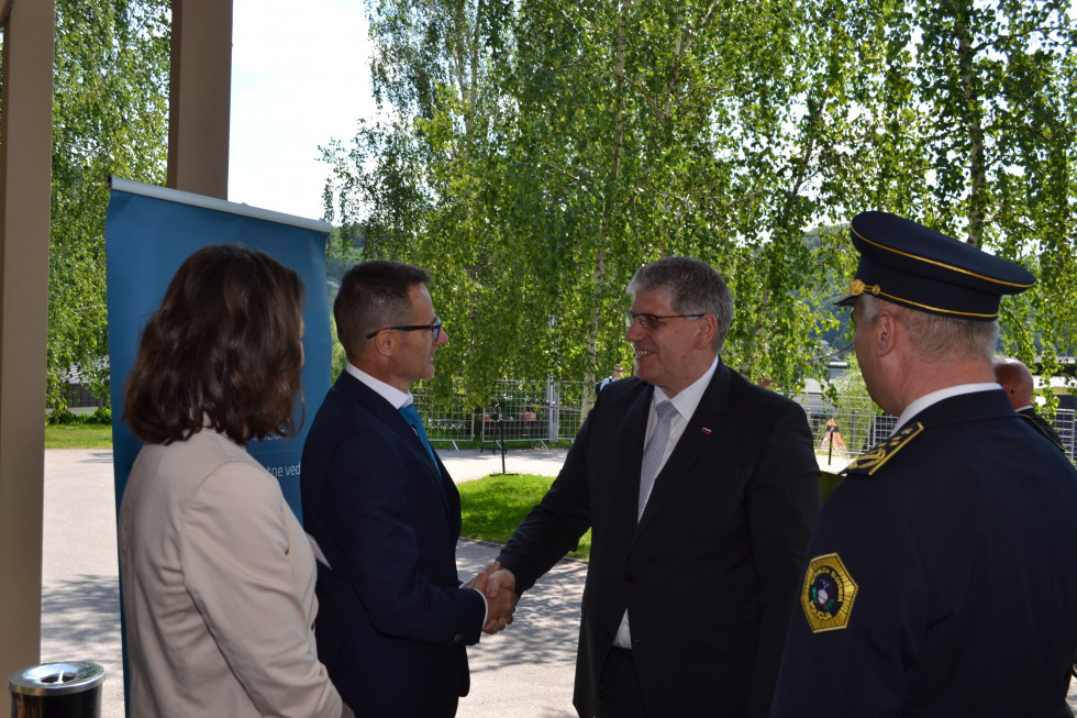 Dekan Fakultete za varnostne vede prof. dr. Igor Bernik in minister za notranje zadeve Boštjan Poklukar se rokujeta. Zadaj zelena drevesa.