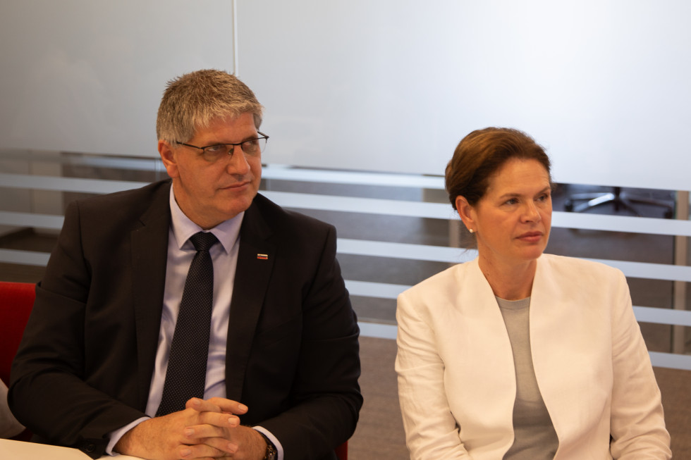 Ministra Boštjan Poklukar in Alenka Bratušek sedita drug ob drugem in poslušata