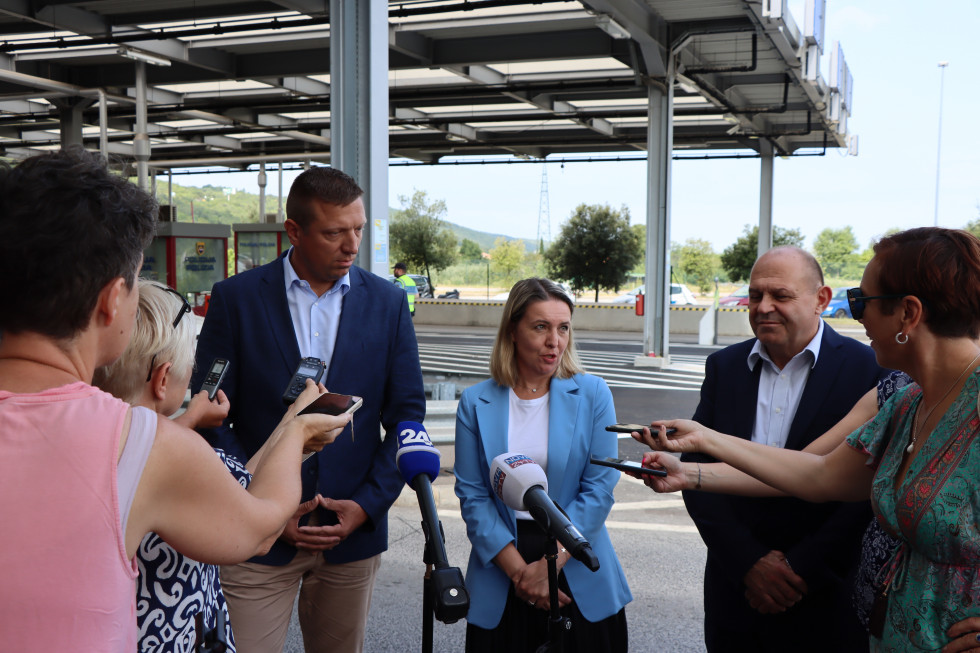 Državna sekretarja Helga Dobrin in Andrej Rajh stojijo na nekdanjem mejnem prehodu Dragonja. Pred njimi novinarji, ki snemajo njuno izjavo. 