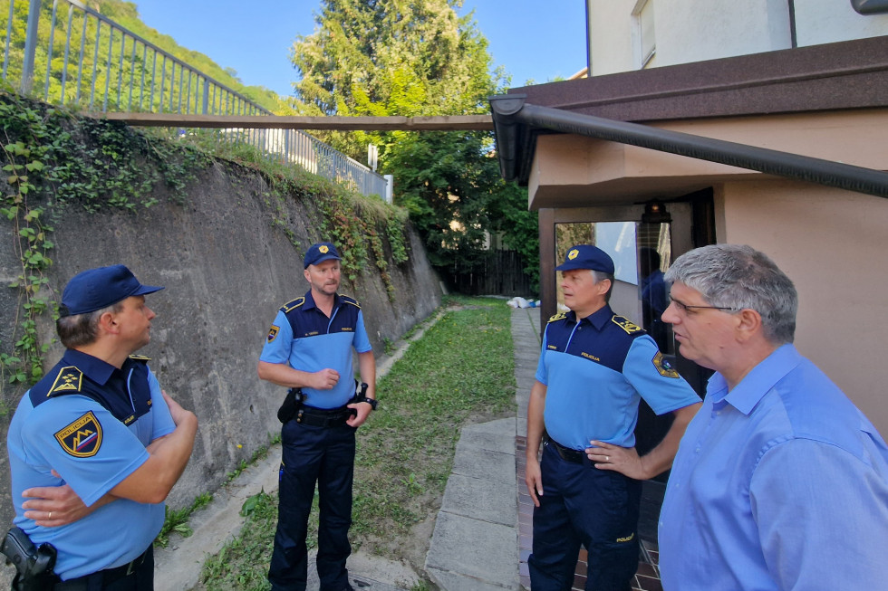 Pogovor ministra s policisti v Laškem. Stojijo v uniformah zunaj pred stavbo.