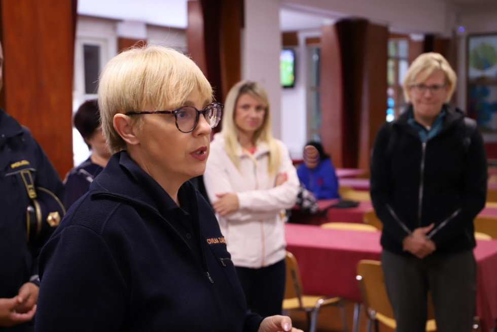 Predsednica republike je obiskala Policijsko akademijo v Tacnu. Stoji spredaj, zadaj državna sekretarka Tina Heferle. V ozadju mize z rdečimi prti.