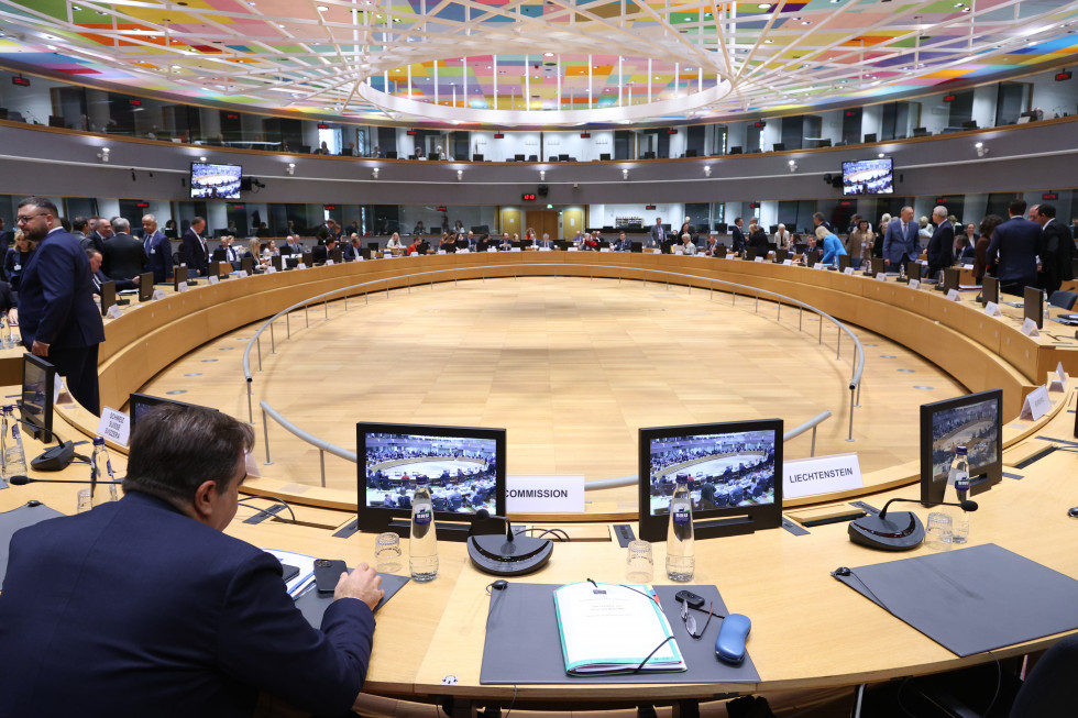 The brown tables are arranged in an oval shape, with chairs behind them for the participants to sit at, and the floor is also brown.