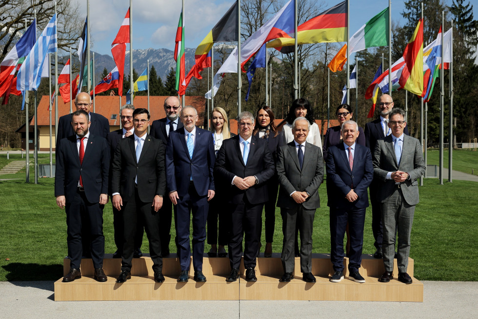 Ministers standing in front of flags outside.