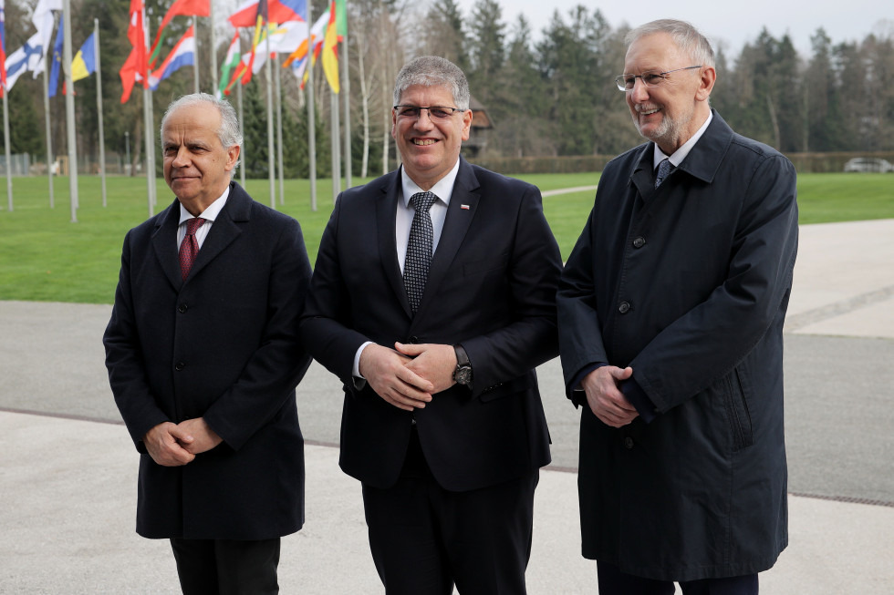 Ministers stand outside, with flags behind them.