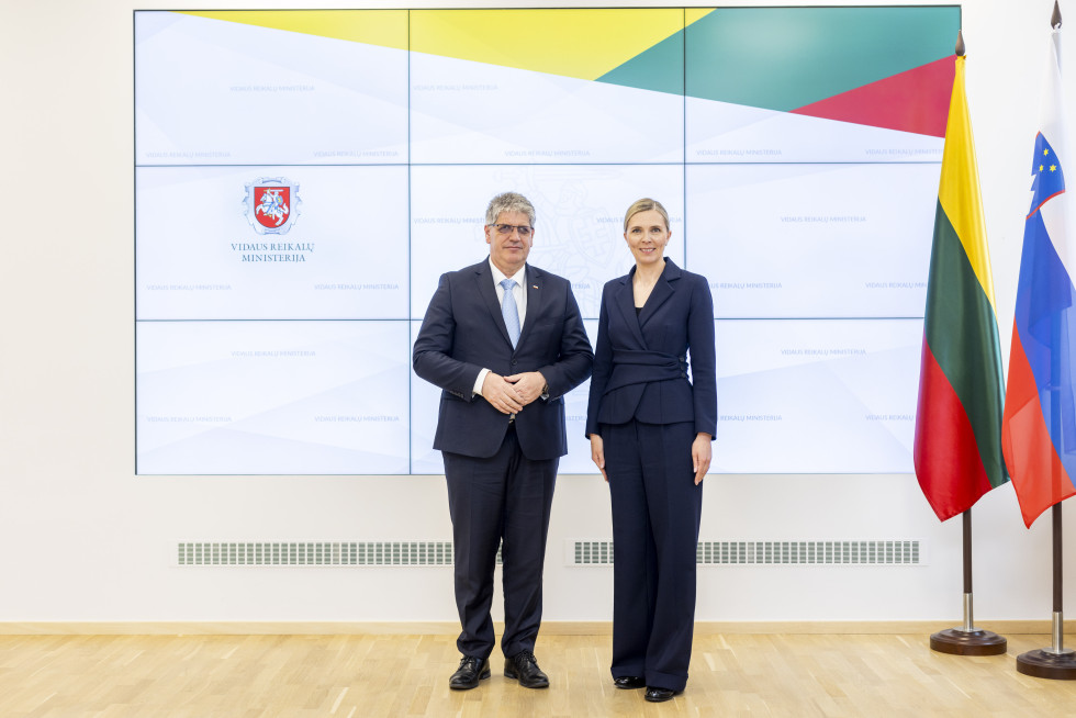 Interior Minister Boštjan Poklukar of Slovenia and Agnë Bilotaitë of Lithuania are standing in front of a photo billboard