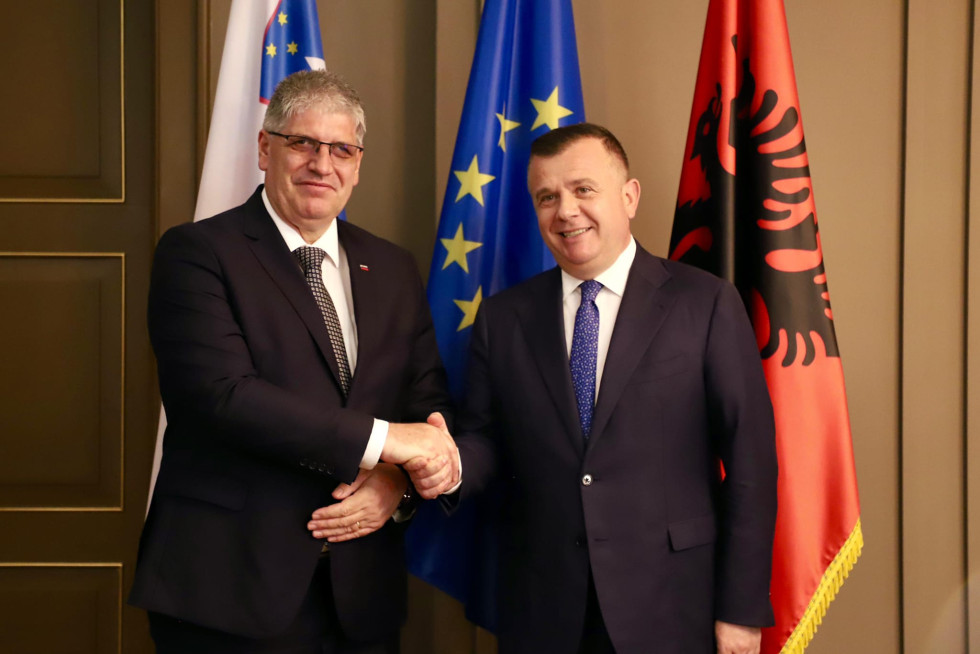 Boštjan Poklukar and Taulant Balla stand and shake hands. Behind them are the flags of Slovenia, the European Union and Albania.