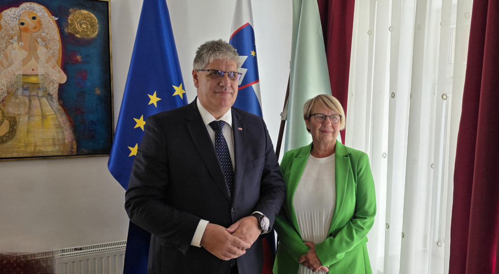 Stojita v notranjosti. Za njima so slovenska, evropska in občinska zastava.