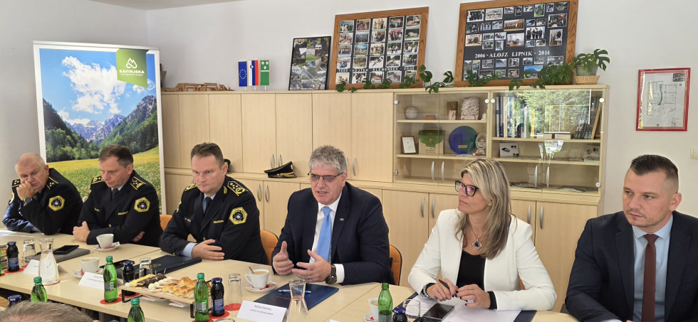 Delegacija ministrstva sedi za mizo bež barve. Za njimi je bela stena in omare bež barve.