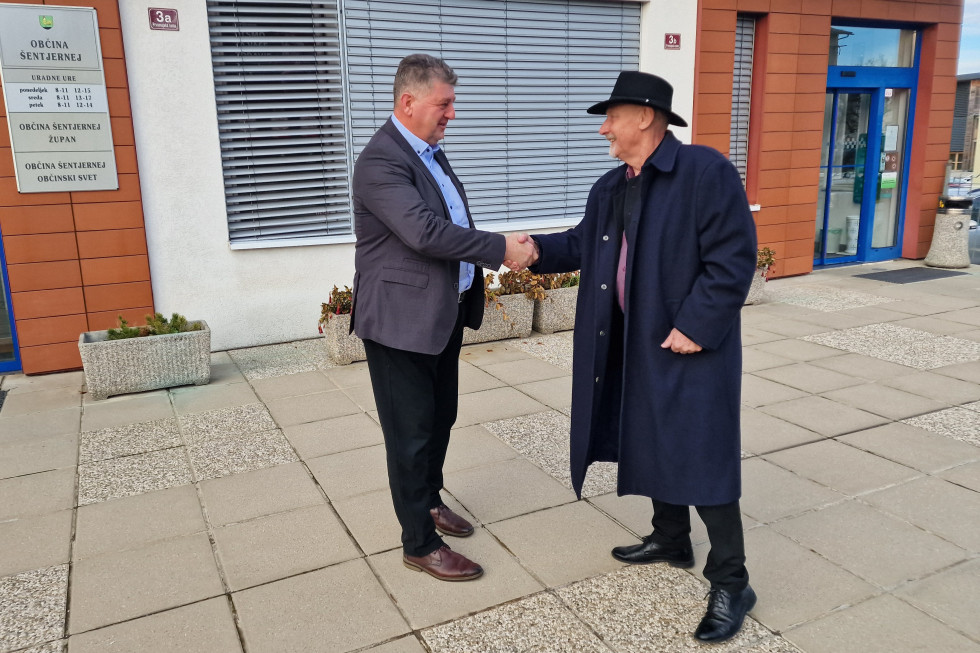 Minister in župan se rokujeta pred vhodom v stavbo