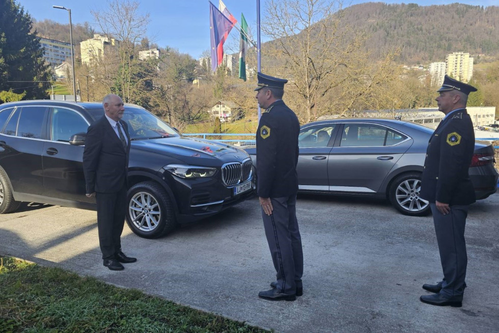 Minister stoji ob avtu, pred njim je policist in ga pozdravlja