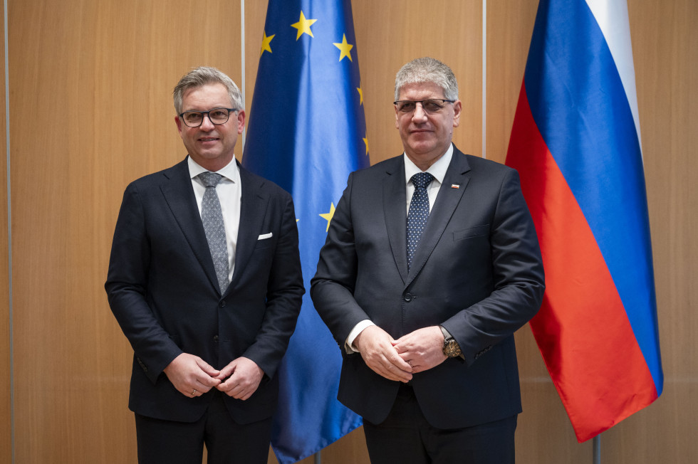 Komisar in minister stojita ob evropski in slovenski zastavi