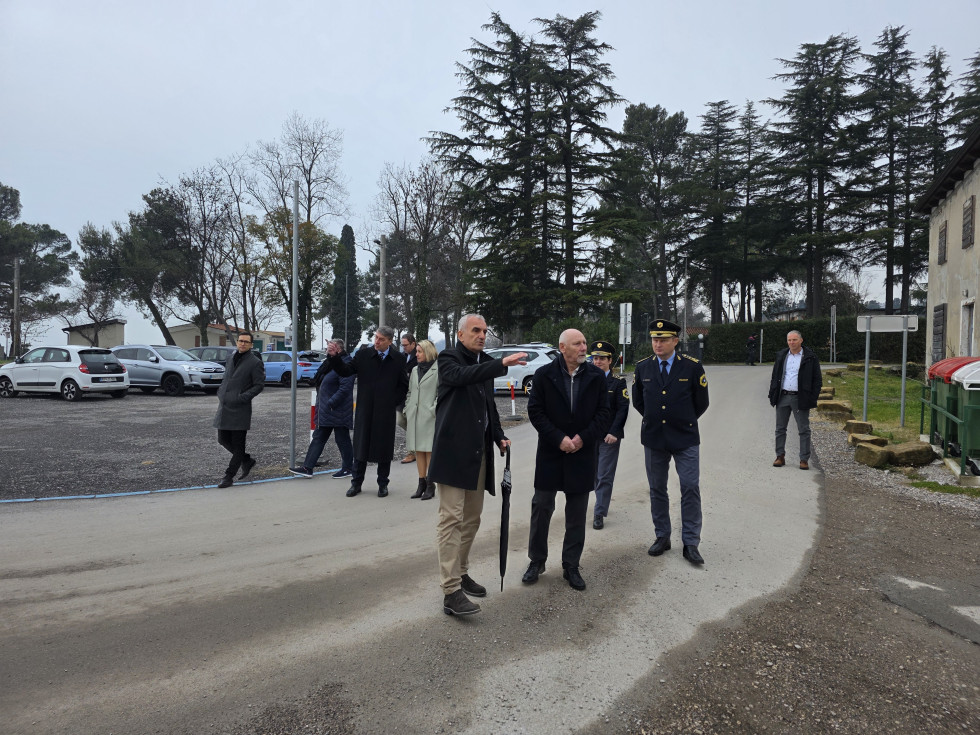 Udeleženci hodijo po športnem parku. Za njimi se vidijo drevesa, vreme je oblačno. 