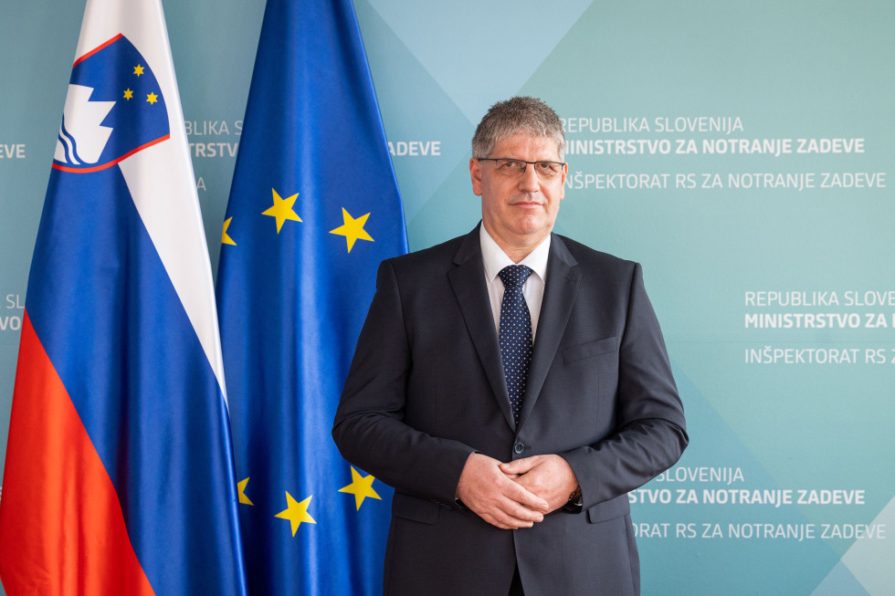 Minister stoji pred modrim ozadjem, na njegovi strani sta slovenska in evropska zastava