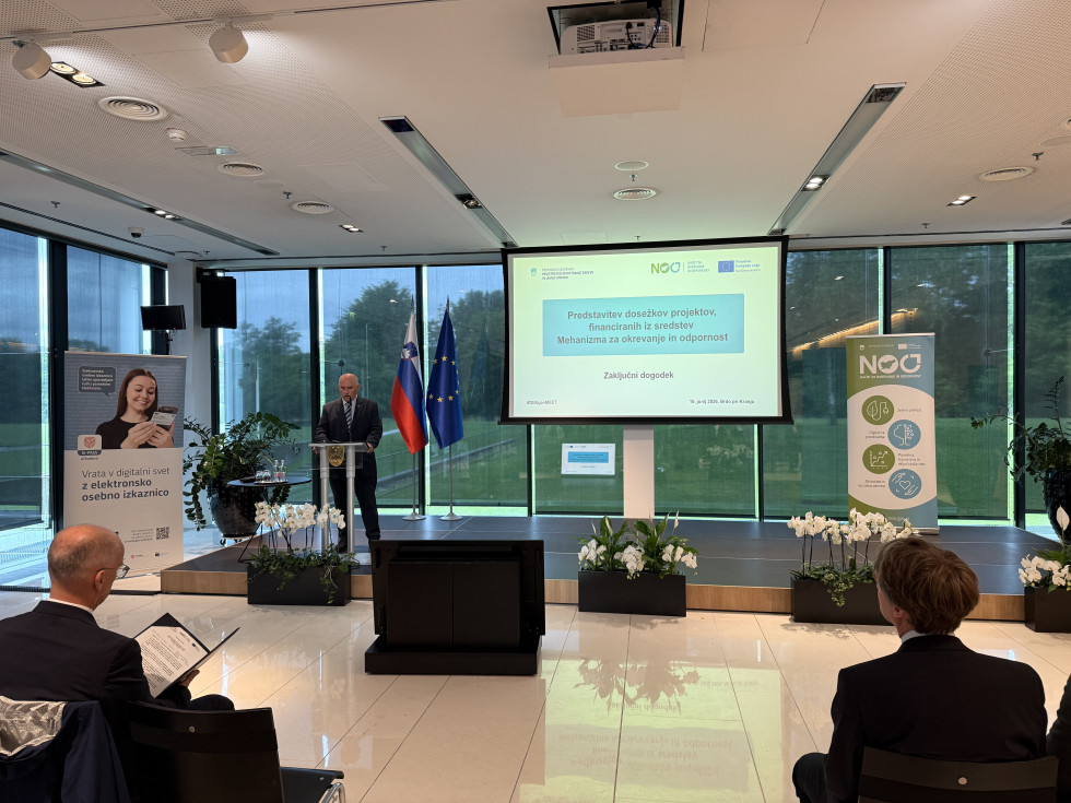 Predstavitev poteka v konferenčnem prostoru, kjer udeleženci spremljajo projekcijo na zaslonu.