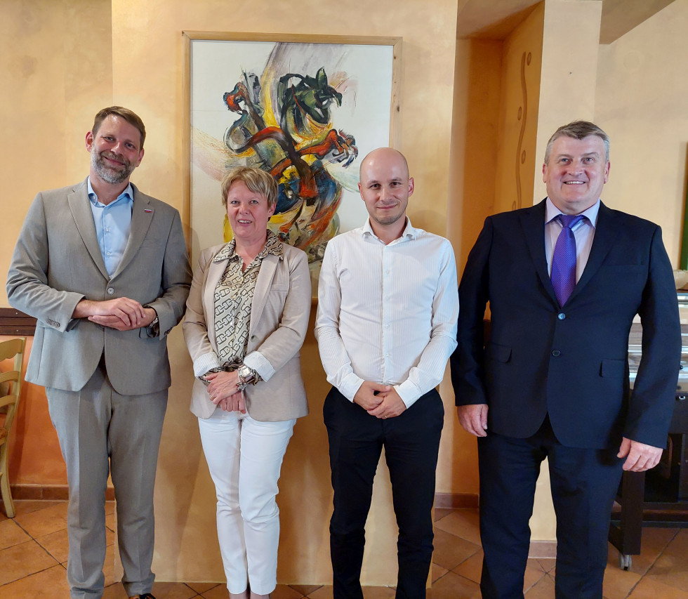 Prisotni stojijo v prostoru in se skupinsko fotografirajo.