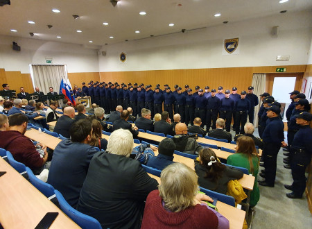 Dvorana z gosti v ospredju, zadaj policisti v dveh vrstah
