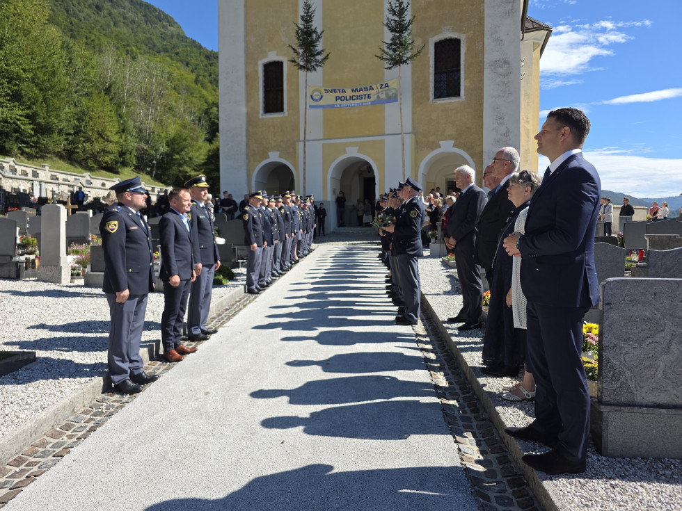 Pogled na cerkev, levo in desno stojijo gostje in policisti. Lep, sončen dan.