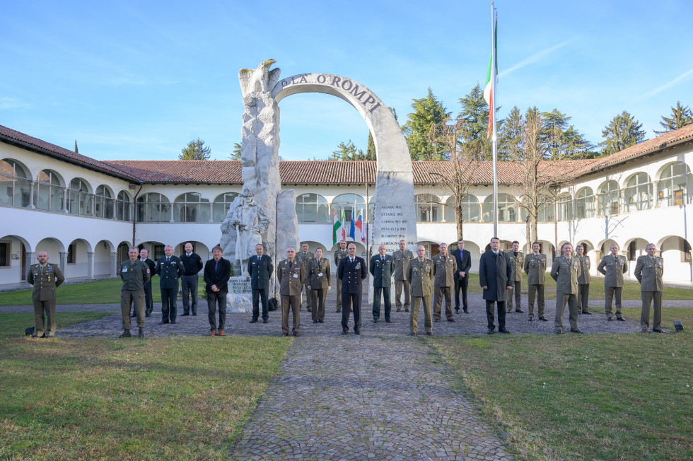 Skupinska fotografija udeležencev zasedanja. V ozadju je velik kamnit vojaški spomenik in stavba z oboki.