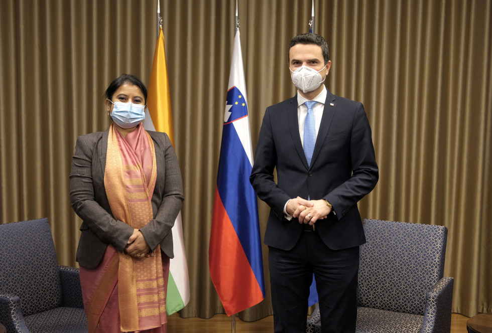 Minister in veleposlanica stojita drug ob drugem v sprejemnici pred zastavami Indije, Slovenije in EU