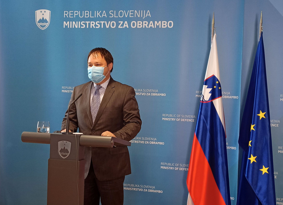 Direktor nove Uprave za vojaško dediščino za govorniškim odrom pred panojem ministrstva in zastavama Slovenije ter EU