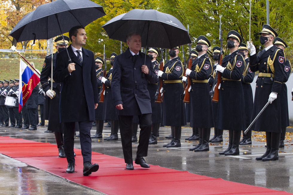 Ministra z dežniki hodita po rdeči preprogi in pregledujeta častno četo Slovenske vojske