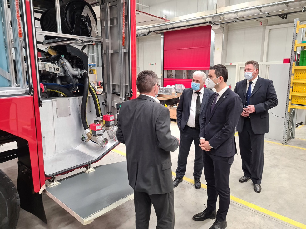 Minister z delegacijo si ogleduje proizvodne prostore in vozila.