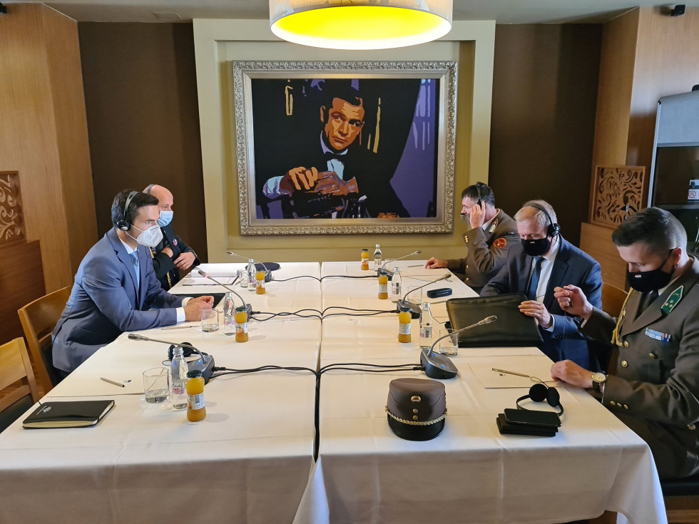 Slovenska in madžarska delegacija na pogovorih za konferenčno mizo. NA steni v ozadju visi umetniška slika.