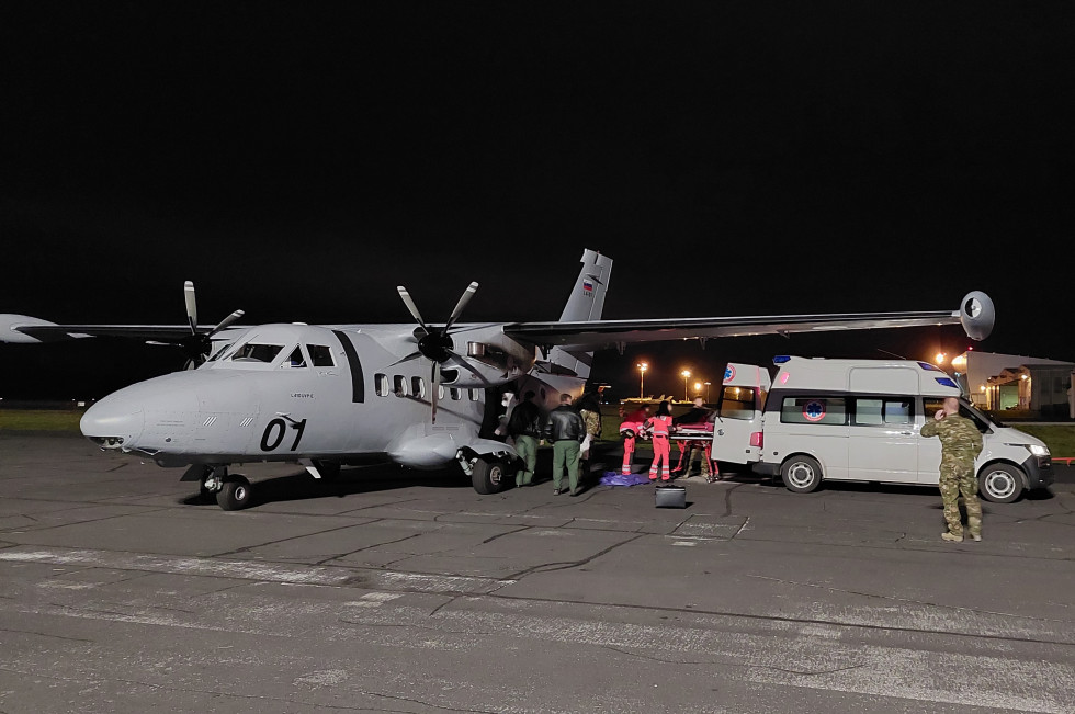 The wounded man is being transferred from the plane standing on the airport runway to an ambulance