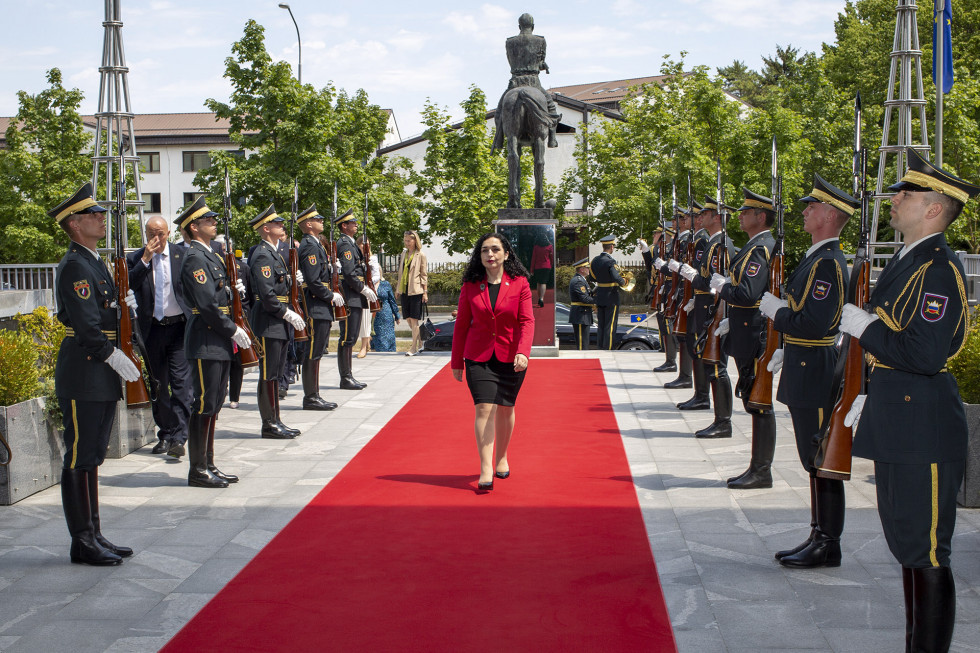 Predsednica hodi prosti vhodu v ministrstvo po rdeči preprogi , med postrojeno častno četo Slovenske vojske