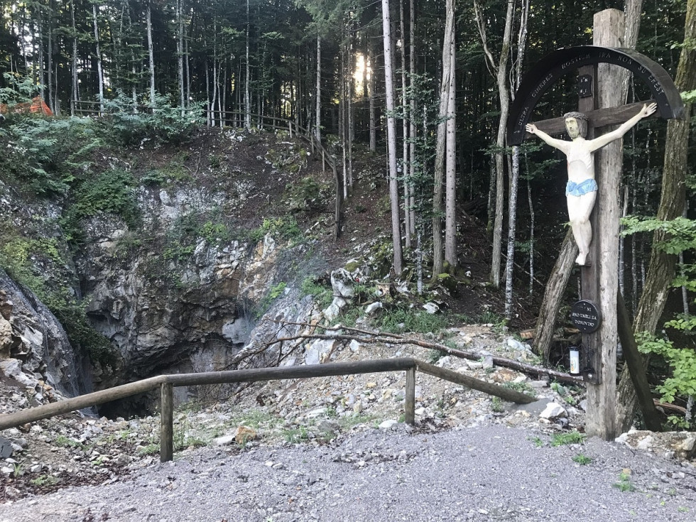 Vhod v jamo je izza lesene ograje. Desno od vhoda stoji razpelo. zadaj pa se začenja gozd