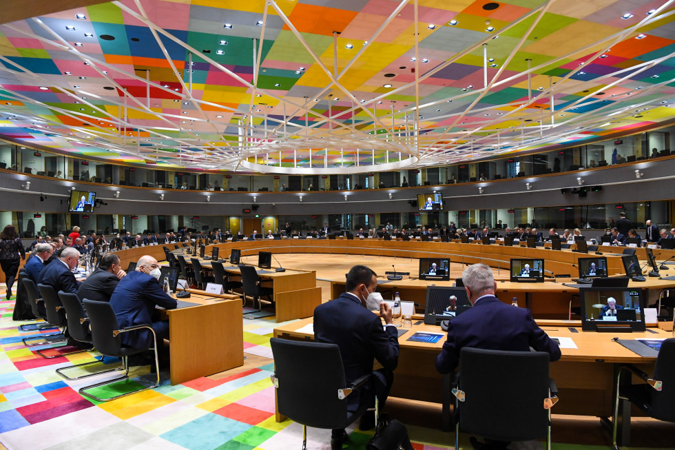 Dvorana kjer je potekalo zasedanje obrambnih in zunanjih ministrov EU. Sedijo za veliko ovalno mizo, nad njimi  je strop s pisanim geometrijskim vzorcem