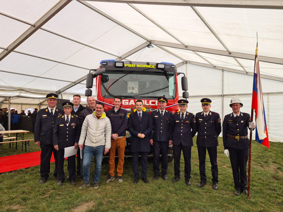 Minister in predstavniki gasilskega društva na skupinski fotografiji pred novim gasilskim vozilom