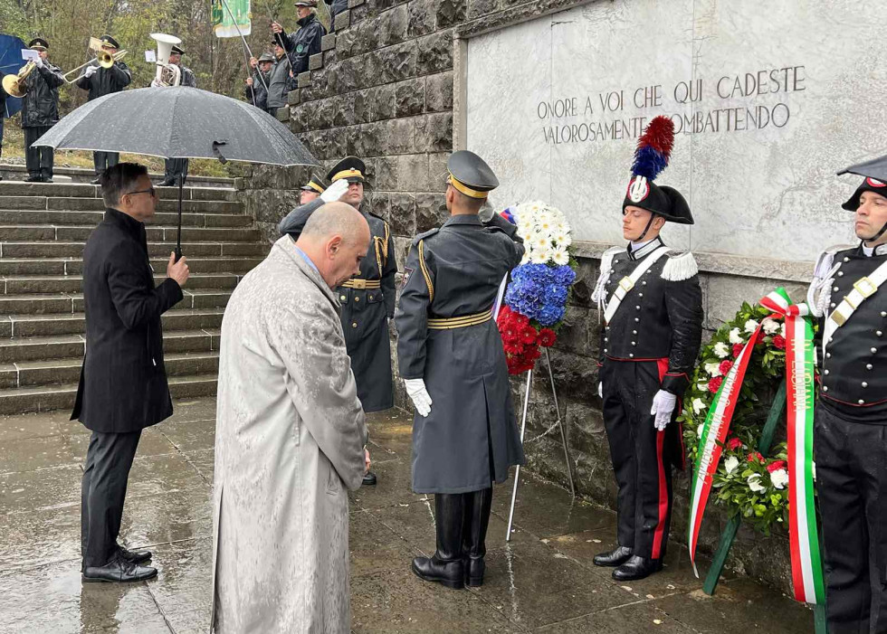 Minister stoji pred pomnikom in položenimi venci. Pred njim so gardisti slovenske in italijanske vojske