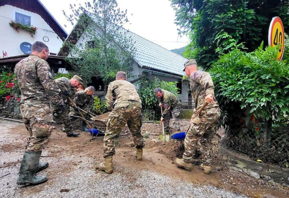 Skupina vojakov z lopatami in drugim orodjem odstranjuje nanose po poplavah