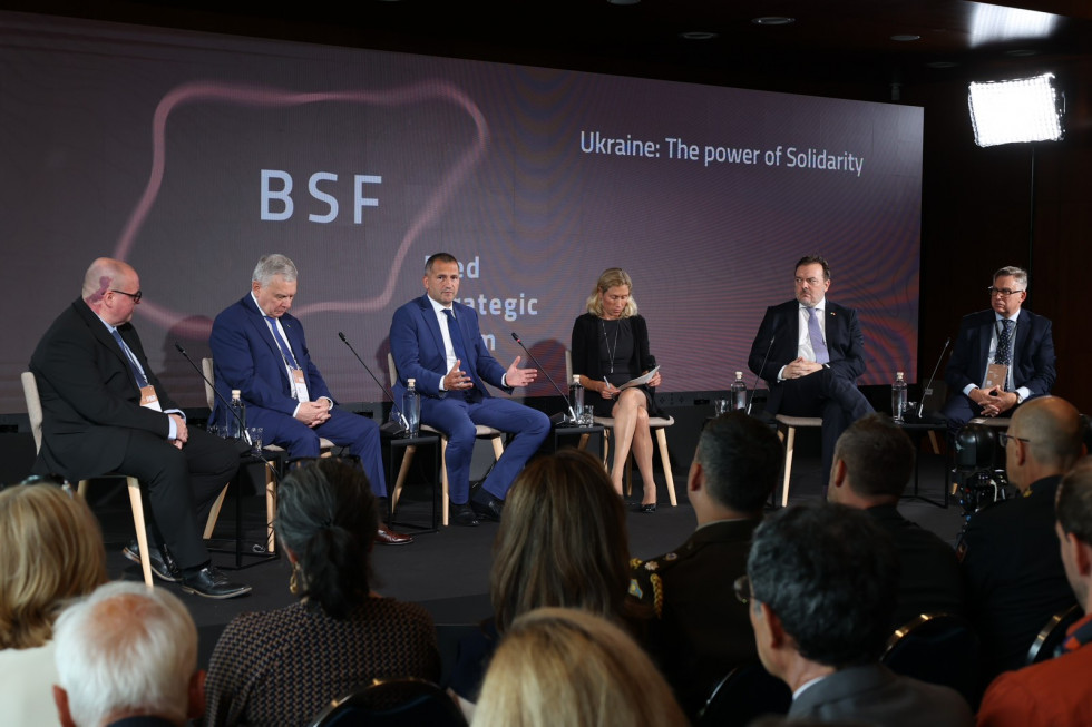 Panelists are seated on stage. Behind them is a billboard with the logo of the Bled Strategy Forum