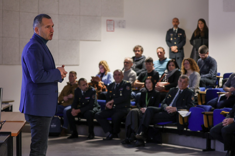 Sekretar stoji med govorom v avditoriju pred udeleženci