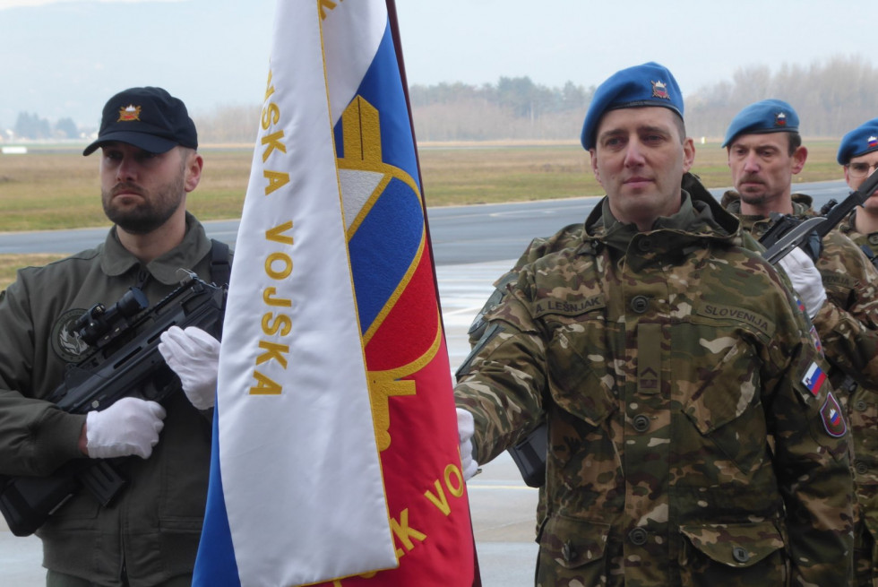 Vojaka stojita v slovesnem postroju z zastavo Slovenske vojske