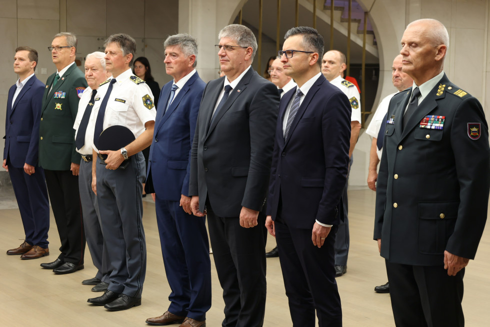 Ministra in drugi visoki gostje stojijo v dvorani pred začetkom slovesnosti
