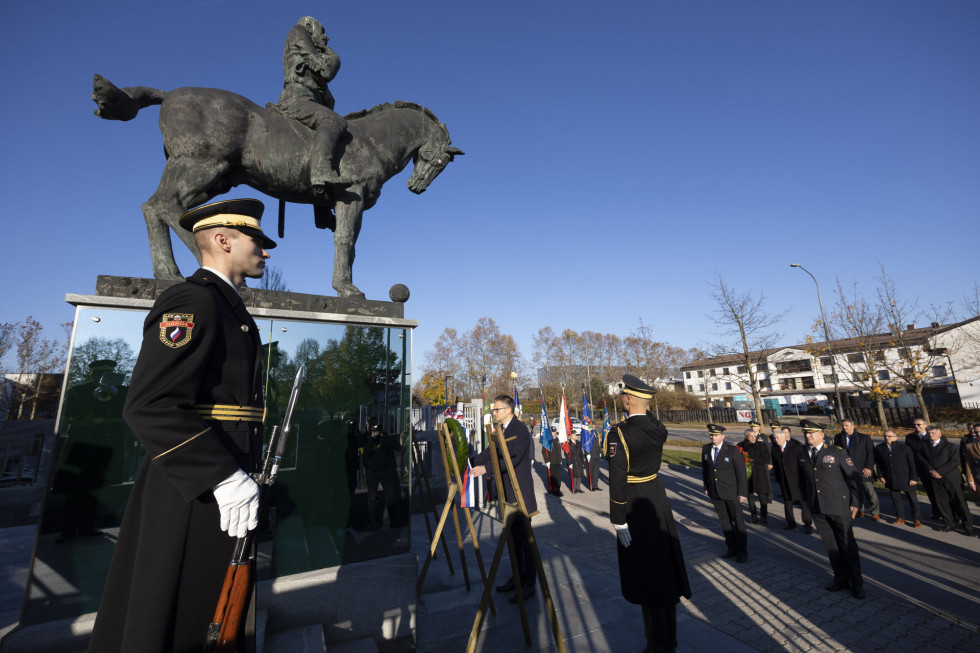 Minister polaga venec pred spomenik generalu Maistru pred stavbo ministrstva. V ospredju je gardist Slovenske vojske.