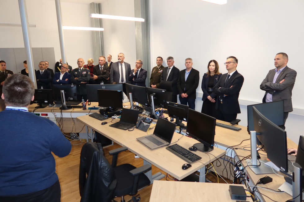 Participants stand at tables with computer equipment