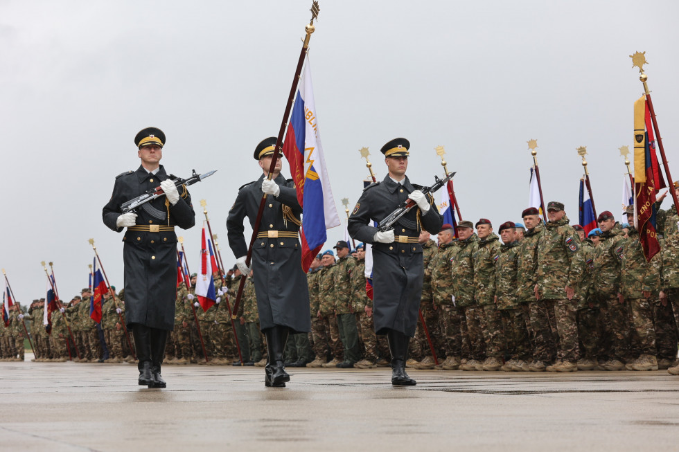 Pripadniki gardne enote nosijo zastavo Slovenske vojske pred postrojenimi vojaki